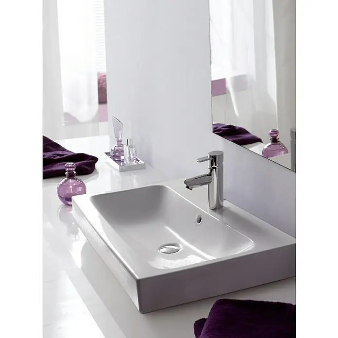 Geberit iCon Aufsatzwaschbecken - 75 x 48,5 cm, Ohne Spezialglasur, Hahnloch: Mitte, Mit Überlauf, Weiß - Das Bild zeigt ein elegantes, rechteckiges Waschbecken in Weiß, das mit einem modernen Chromhahn und lila Accessoires stilvoll in Szene gesetzt wurde.