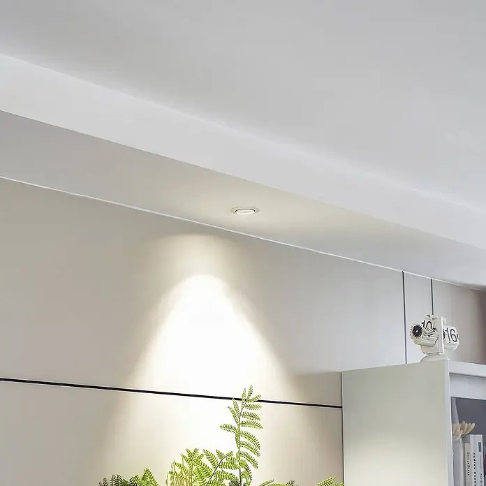 Arcchio Deckenstrahler Harcos - weiß / opal - Weiße Einbauleuchte strahlt einen fokussierten Lichtstrahl auf eine Wand in einem modernen Raum.