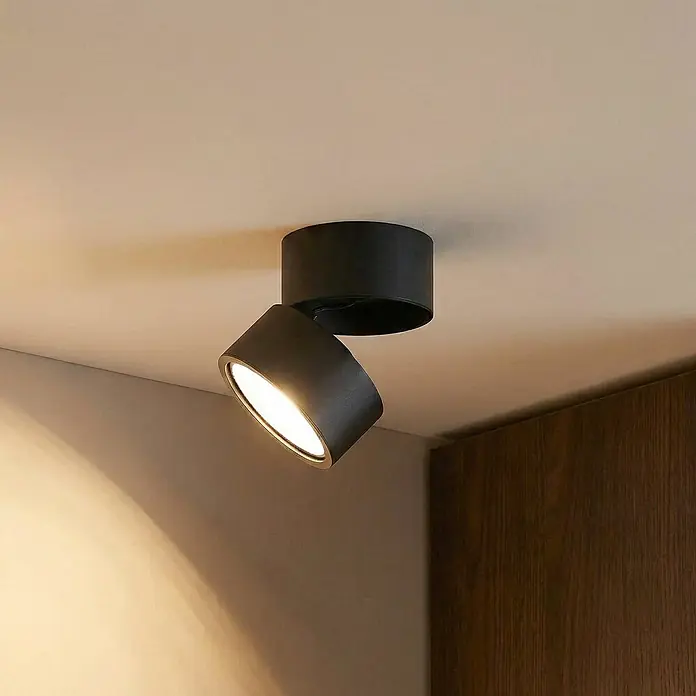Lindby Deckenstrahler Thorid - schwarz, schwarz, G9 - Schwarzer zylindrischer Deckenstrahler, zur Beleuchtung einer Wand geneigt.