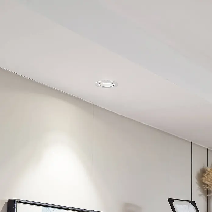 Arcchio Deckenstrahler Harcos - weiß / opal - Ein weißer Einbaustrahler in einer Decke, der Licht auf eine helle Wand wirft.
