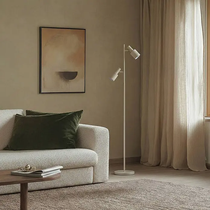 Lindby Stehleuchte Ovelia - Höhe: 155 cm, creme / amber, creme / amber, E27 - Beiges Sofa mit grünen Kissen und weißer Doppelkopf-Stehlampe in einem modernen Wohnzimmer.