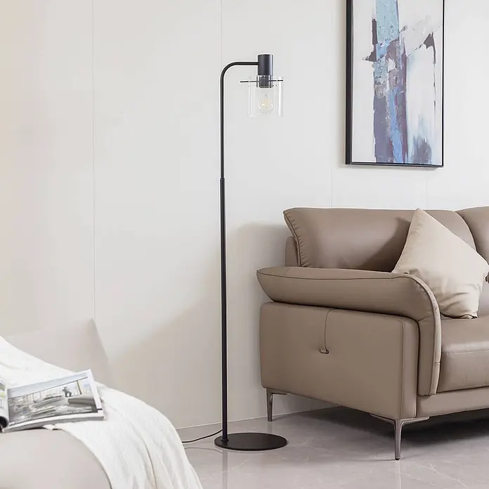 Lucande Stehleuchte Eirian - Höhe: 150 cm, schwarz, klar / transparent, E27 - Schwarze Stehlampe aus Metall mit klarem Glasschirm, neben einem hellbraunen Sofa im Wohnzimmer.
