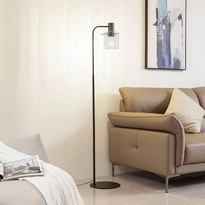 Lucande Stehleuchte Eirian - Höhe: 150 cm, schwarz, klar / transparent, E27 - Schwarze Stehlampe aus Metall mit klarem Glasschirm beleuchtet modernes Wohnzimmer neben beigem Sofa.