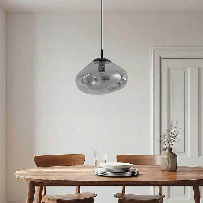 Lindby Pendelleuchte Lelia - L x B x H: 35 x 35 x 22 cm, alu / grau / zink, rauchgrau, sandSchwarz, E27 - Graue, unregelmäßige Glas-Pendelleuchte mit schwarzer Halterung hängt über einem Esstisch aus Holz.