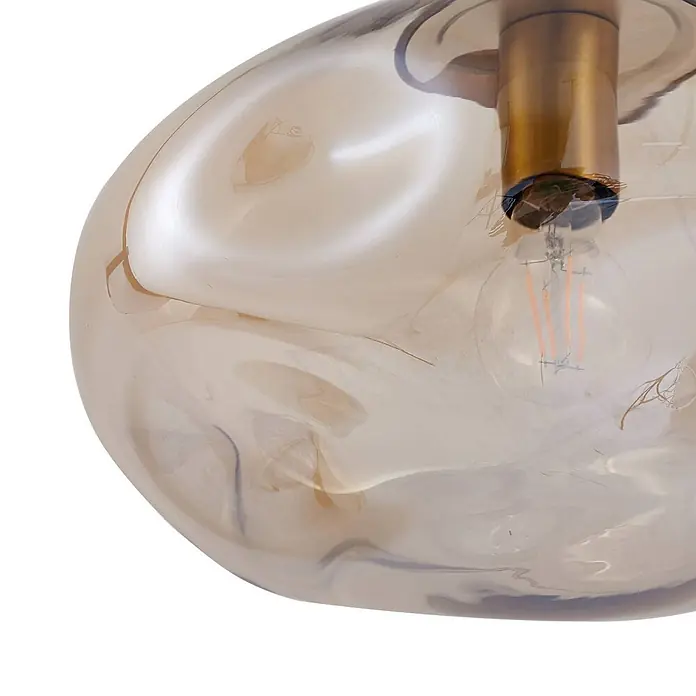 Lindby Pendelleuchte Lelia - L x B x H: 35 x 35 x 22 cm, creme / amber, amber, messing, E27 - Nahaufnahme einer bernsteinfarbenen Glas-Pendelleuchte mit unregelmäßigen Wirbeln, Messingfassung und LED-Filamentbirne.