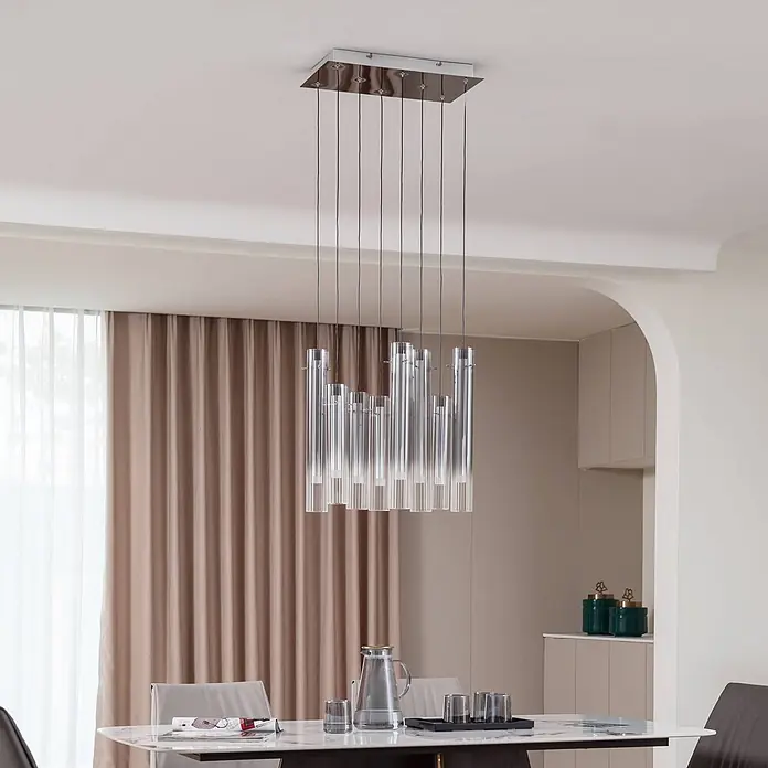 Lucande Pendelleuchte Korvitha - alu / grau / zink, rauchgrau, silber - Moderne Hängelampe mit klaren Glasröhren und rechteckiger Chrombasis über einem Esstisch.