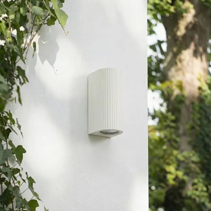 Lindby Außenwandleuchte Aluvo - weiß / opal, IP65 - Weiße geriffelte Außenwandleuchte an einer Wand.
