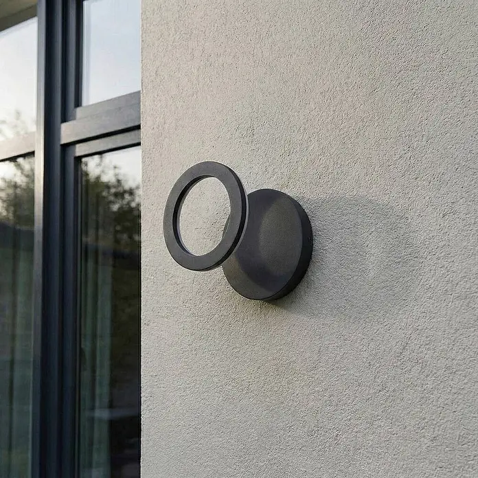 Lindby Außenwandleuchte Ilveo - schwarz, schwarz, IP54 - Dunkelgraue runde Außenwandleuchte mit ringförmigem Diffusor, an einer Wand montiert.
