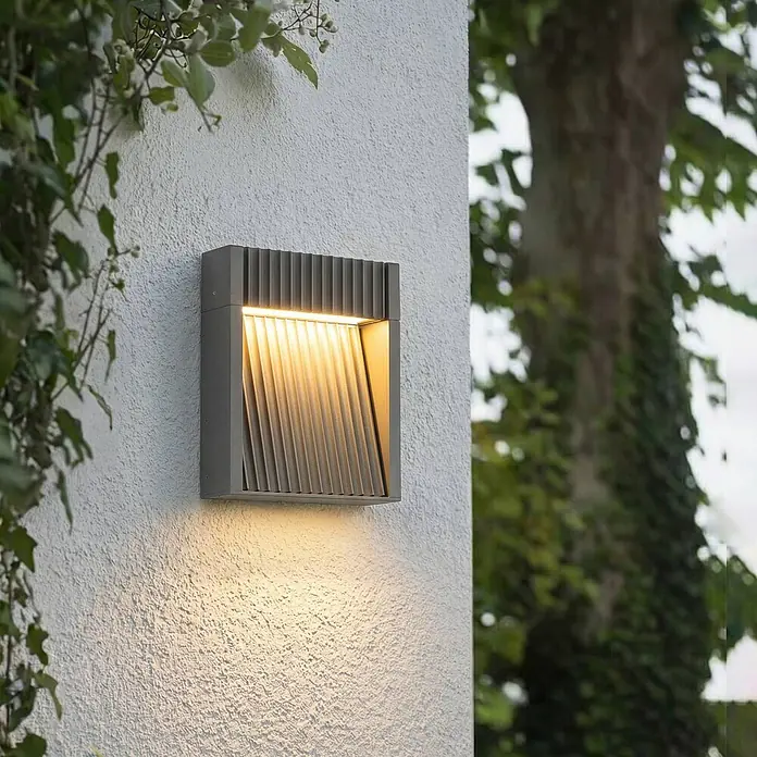 Lucande Außenwandleuchte Tavion - schwarz, schwarz, IP65 - Dunkelgraue Außenwandleuchte mit Lamellendesign, die warmes Licht wirft.