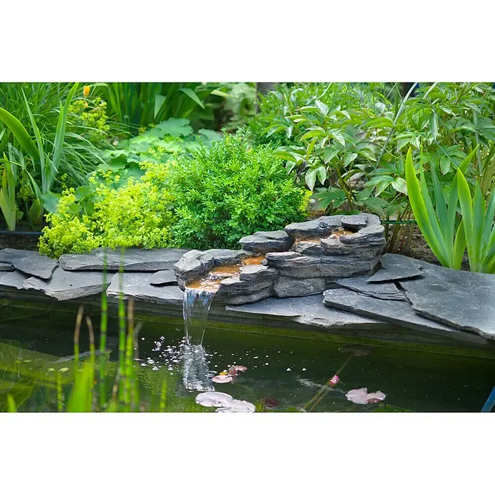 Ubbink Einbau-Wasserfall Cazorla - 74 x 34 x 29 cm, Polyresin, LED - Gartenteich mit kleinem Wasserfall, umgeben von grünen Pflanzen und Steinen, die eine beruhigende Atmosphäre schaffen.