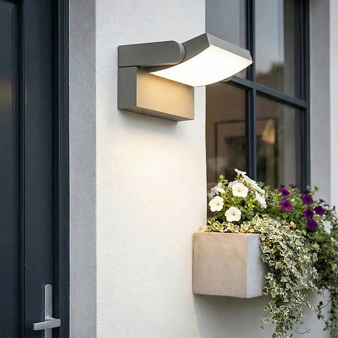 Lindby Außenwandleuchte Sherin - alu / grau / zink, IP54 - Graue, verstellbare LED-Außenwandleuchte an einer Hauswand, die Licht nach oben und unten abgibt.
