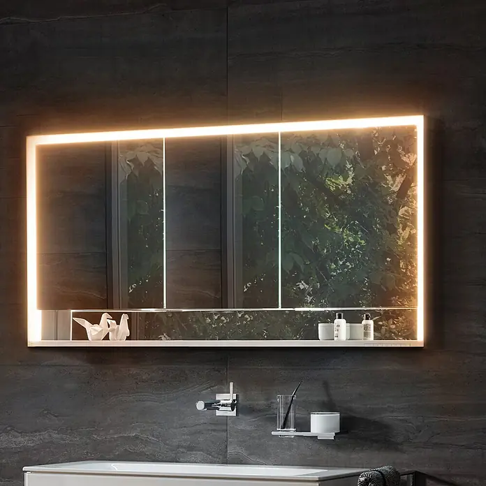 Keuco LED-Spiegelschrank Royal Lumos - B x H: 120 x 73,5 cm, Aluminium, silber-eloxiert - Rechteckiger Badspiegelschrank mit LED-Beleuchtung und Ablage, auf dunkler Fliesenwand mit Pflegeprodukten und Deko.