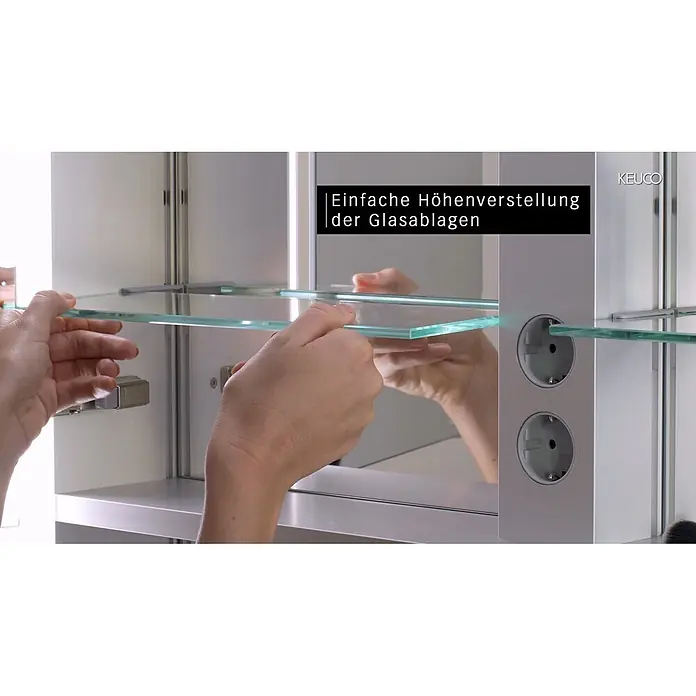 Keuco LED-Spiegelschrank Royal Lumos - B x H: 100 x 73,5 cm, Aluminium, silber-eloxiert - Hände verstellen eine Glasablage in einem Spiegelschrank. Einfache Höhenverstellung der Glasablagen und integrierte Steckdosen.