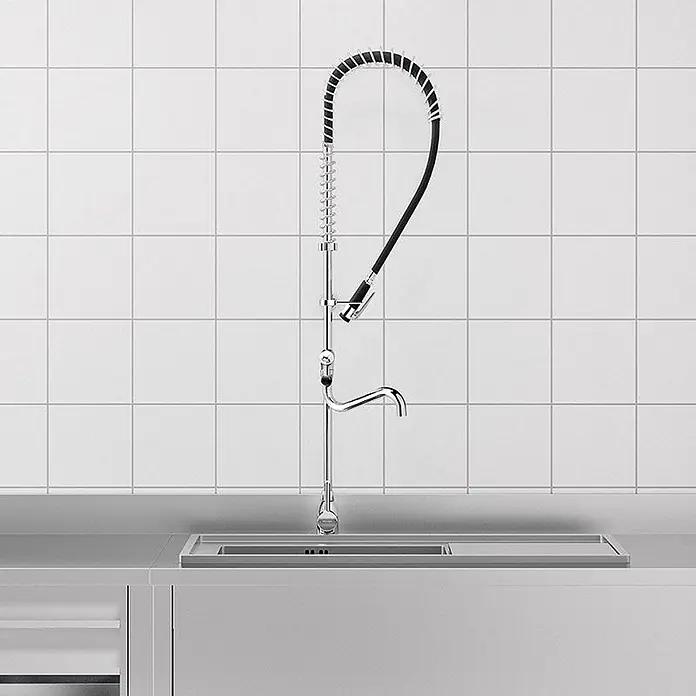 Delabie Spültischarmatur Delabie -  - Verchromte Gastro-Küchenarmatur mit Vorspüldusche und Standardauslauf über einem Spülbecken.