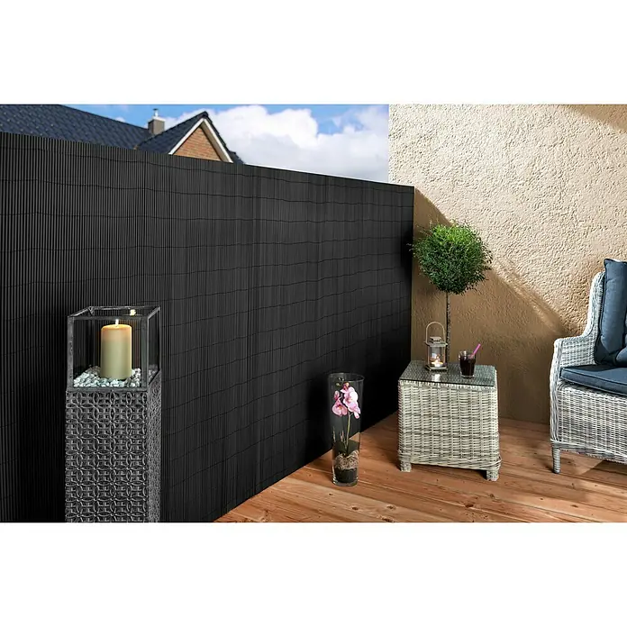 Sichtschutzmatte - 300 x 180 cm, Kunststoff, Anthrazit - Schwarzer Sichtschutzzaun aus Bambus mit dekorativen Elementen und Gartenmöbeln auf einer Terrasse.