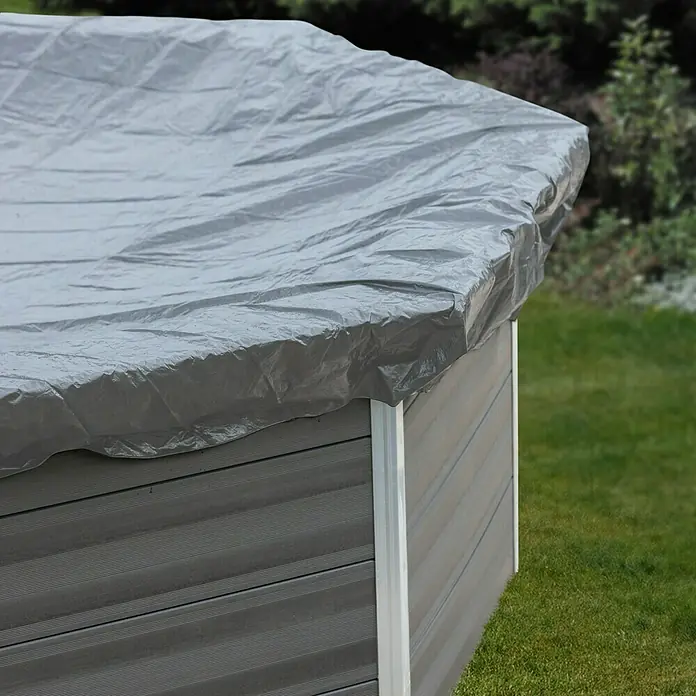 Gre Pool-Abdeckplane Winter - 580 g/m², L x B: 688 x 408 cm, Kunststoff - Eine graue Plane bedeckt einen Whirlpool im Garten, schützt ihn vor Witterungseinflüssen und Schmutz. Die Abdeckung ist leicht zerknittert.