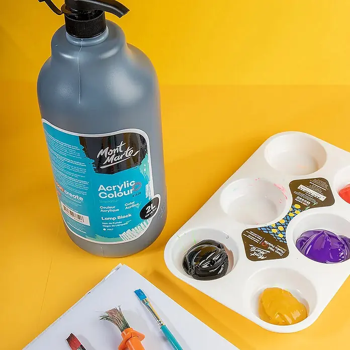 Mont Marte Acrylfarbe Signature - Lampenschwarz, 2.000 ml, Flasche mit Tropfpipette - Große Mont Marte Lamp Black Acrylfarbflasche mit Pumpe, Palette mit Farben und Pinsel auf gelbem Untergrund.