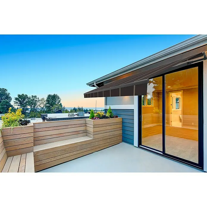 SmartSun Toldo de brazos extensibles Noir Limited Edition Kit - Gris oscuro, Ancho: 4 m, Caída: 2,5 m - Un elegante toldo marrón que protege un patio con bancos de madera y jardineras. El toldo proporciona sombra y confort.