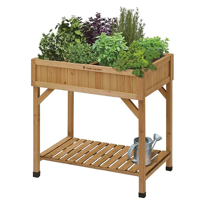 VegTrug Kräuterhochbeet - Material: Holz - Hellbraunes Holz-Hochbeet mit verschiedenen Kräutern, darunter eine Lamellenablage mit einer Metallgießkanne.