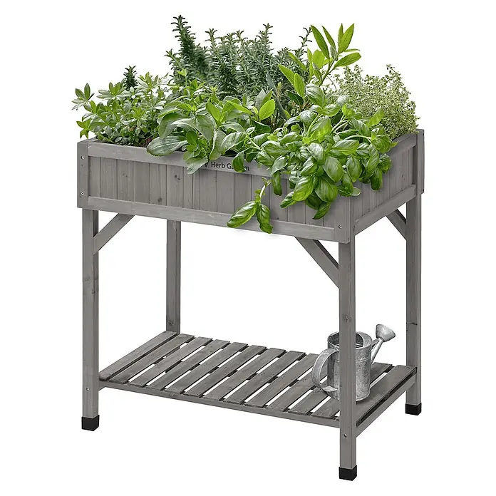 VegTrug Kräuterhochbeet - Material: Holz - Grauer Hochbeet-Kräutergarten aus Holz mit verschiedenen grünen Kräutern, darunter ein Lattenregal mit einer Metallgießkanne.