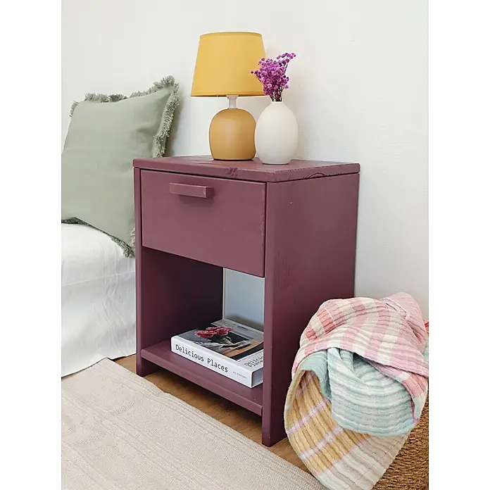 Astigarraga Vita Mesita de noche - L x An x Al: 25 x 40 x 50 cm, Natural, Número de cajones: 1 ud. - Mesita de noche de madera color ciruela con un cajón y un estante abierto, junto a una cama.