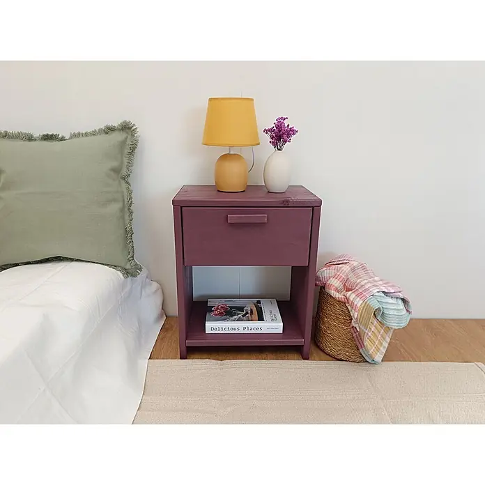 Astigarraga Vita Mesita de noche - L x An x Al: 25 x 40 x 50 cm, Natural, Número de cajones: 1 ud. - Mesita de noche de madera morada oscura con un cajón y un estante abierto, junto a una cama.