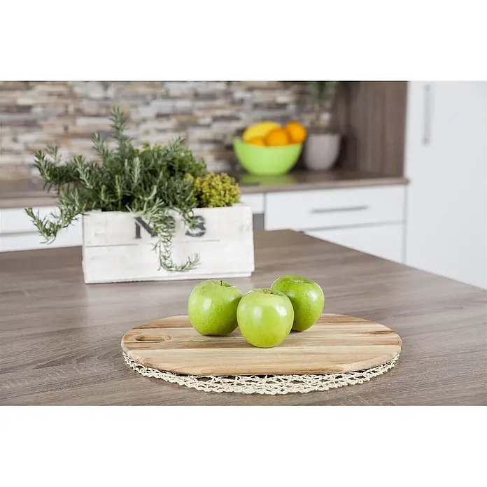 Pflanzen für dich Obstbaum 150-200cm - Malus domestica 'Granny Smith' - Drei grüne Äpfel auf einem runden Holzschneidebrett mit gehäkelter Unterlage, auf einer Küchentheke.