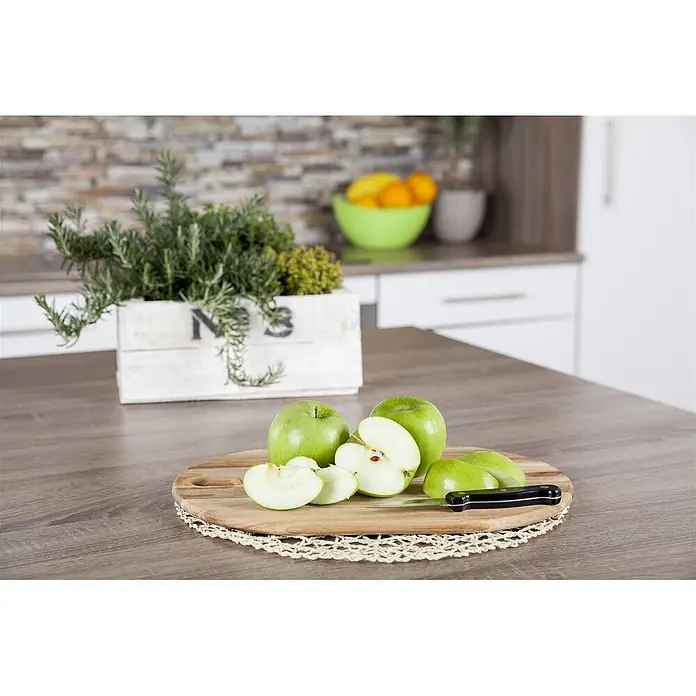 Pflanzen für dich Obstbaum 150-200cm - Malus domestica 'Granny Smith' - Grüne Äpfel, ganz und geschnitten, auf einem runden Holzschneidebrett mit Messer in einer Küche.