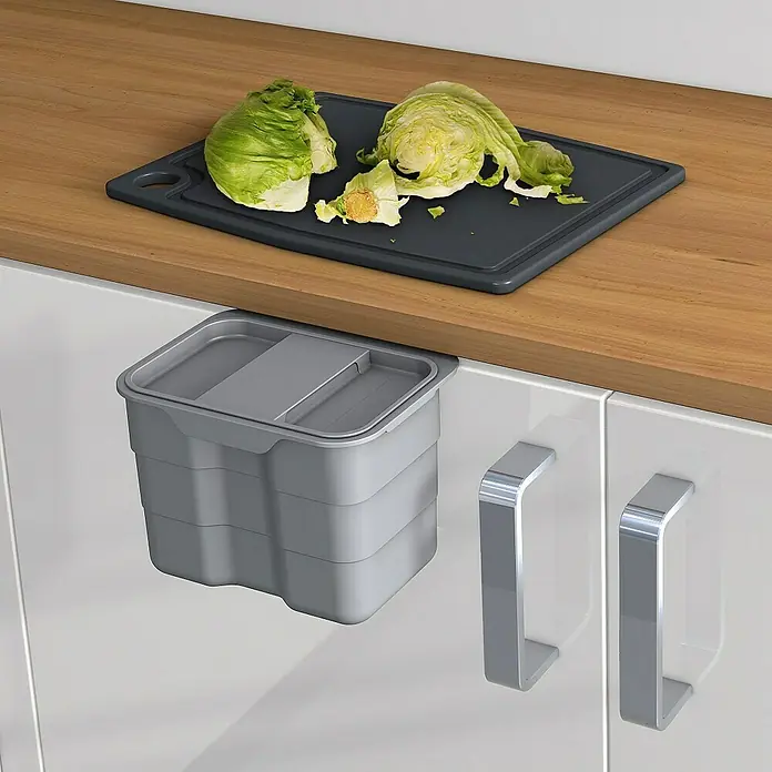 essensa Einbaumülleimer Biobin Aufbewahrungsbox - 4,2 l, Kunststoff, Hellgrau - Ein grauer, hängender Abfallbehälter unter einer Arbeitsplatte, neben einer grauen Schneidebrett mit Salat.