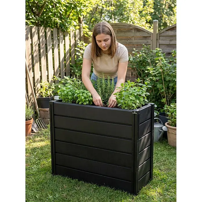 KHW Hochbeet Demeter - XXL schmal - 158 x 44 x 92 cm, Kunststoff, Anthrazit - Schwarzes Lamellen-Hochbeet im Garten, mit einer Person, die Kräuter pflanzt.