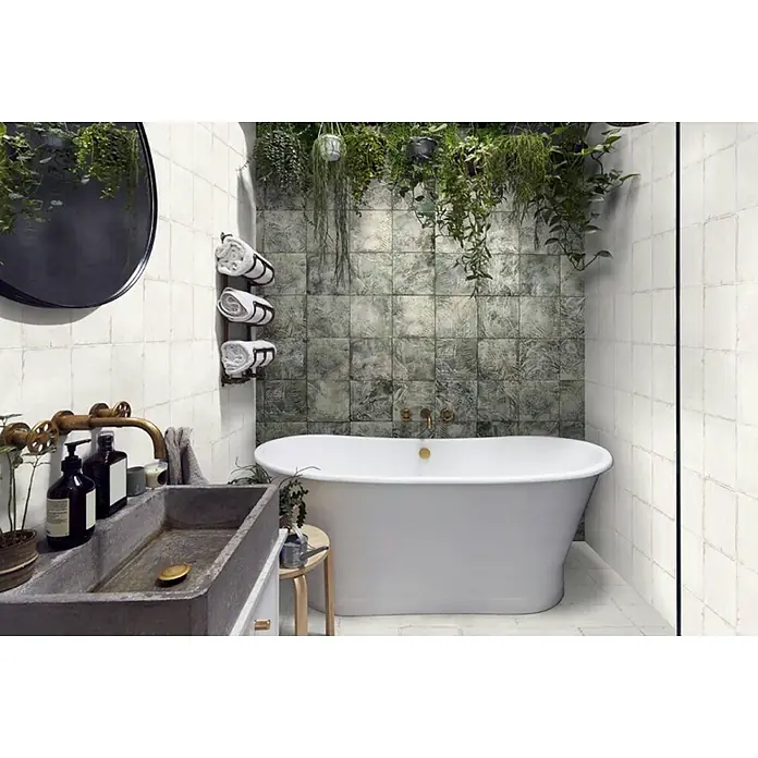 Feinsteinzeugfliese Calma Blanco - 24,8 x 24,8 cm, Weiß, Matt - Ein modernes Badezimmer mit weißen quadratischen Wandfliesen und dunkelgrünen botanisch gemusterten Fliesen um eine freistehende Badewanne.