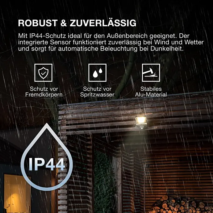 Ledvance LED-Sensor-Strahler Endura - 10 W, L x B x H: 16,8 x 10,8 x 6,3 cm, Grau, IP44 - Ein robustes, dunkles IP44-Outdoor-Flutlicht aus Aluminium an einer Holzwand, leuchtet bei Regen.