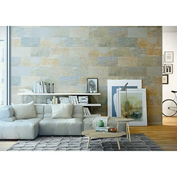 Bariperfil Perfil de acabado angular Cuarcita - 2,6 m x 3 cm - Esta imagen muestra un diseño de interiores moderno con una pared de acento de imitación de piedra. Un sofá de color claro y una alfombra estampada completan el conjunto.