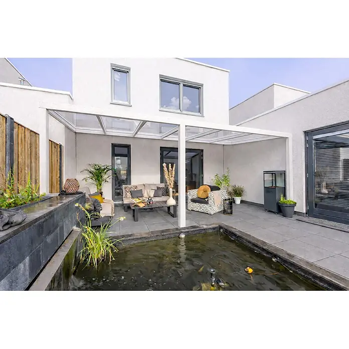 Gardendreams Terrassenüberdachung Essence - B x T: 600 x 335,5 cm, Reinweiß, Verbundsicherheitsglas (VSG), Klar - Weiße Pergola überdacht eine moderne Terrasse mit gemütlicher Sitzecke und Zierteich.