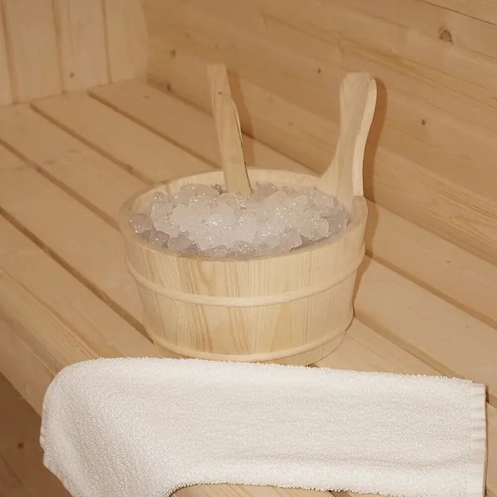 Home Deluxe Fasssauna LAHTI XL - Elektroofen, Holz, L x B x H: 220 x 189 x 191,5 cm - Holzeimer mit Eiswürfeln und zwei Schaufeln auf einer Saunabank neben einem weißen Handtuch.