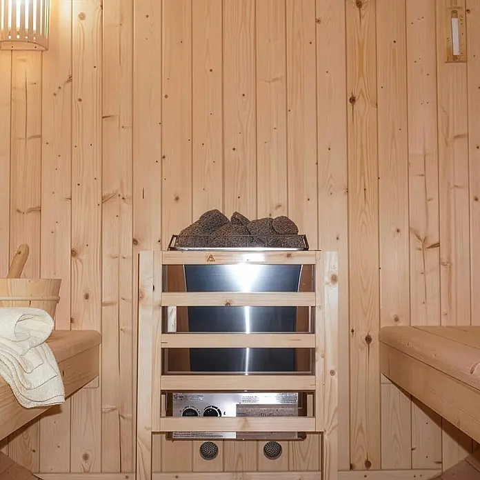 Home Deluxe Fasssauna LAHTI XL - Elektroofen, Holz, L x B x H: 220 x 189 x 191,5 cm - Ein Saunaofen aus Edelstahl mit Holzrahmen und dunklen Saunasteinen, in einer hellen Holzsauna mit Bänken.