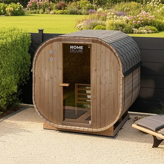 Home Deluxe Fasssauna CUBE XL - Elektroofen, Holz - Eine Holzfasssauna aus Naturholz steht im Freien.