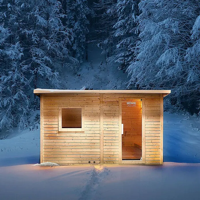 Home Deluxe Fasssauna TALO XL - Elektroofen, Holz - Helle Holzsauna-Kabine mit Glastür und Fenster, von innen beleuchtet, in einem verschneiten Wald.