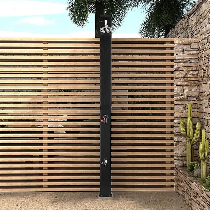 Home Deluxe Solardusche OLYMP - Kunststoff, Schwarz Matt, 40 l - Schwarze Außendusche mit modernem Design, installiert vor einer hölzernen Sichtschutzwand in einem Garten.