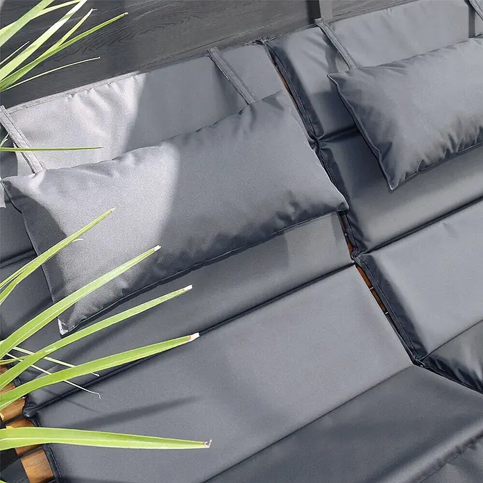 Home Deluxe Gartenliege TAIGA inkl. 1 Auflage - Natur, Holz - Nahaufnahme von grauen Outdoor-Kissen und rechteckigen Polstern auf einer hölzernen Gartenliege, mit grünen Pflanzenblättern.