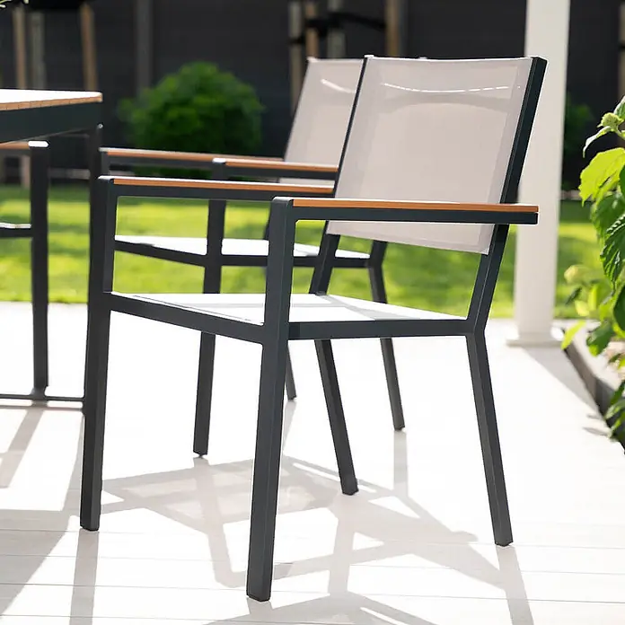 Home Deluxe Gartentisch-Set CANTOS SEDIA -  - Dunkelgrauer Metall-Gartenstuhl mit hellem Stoffbezug, Rückenlehne und Holzarmlehnen auf einer Terrasse.