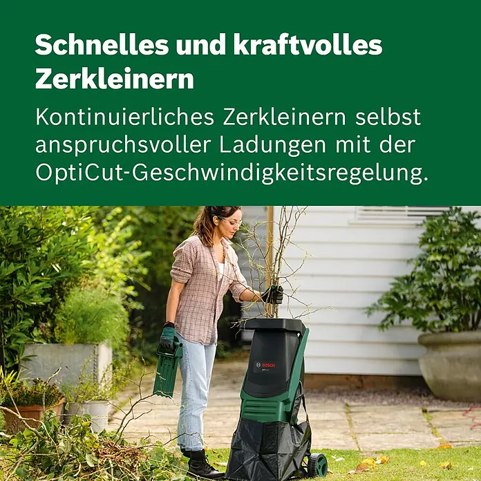 Bosch Elektro-Messerhäcksler Axt Rapid 2000 - Max. Aststärke: 3,5 cm, 2.000 W - Eine Frau nutzt einen grünen und schwarzen Bosch Gartenhäcksler, um Äste in einem Garten zu zerkleinern.