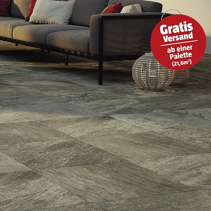 Atlas Concorde Solution Regent Terrassenfliese Grey - 60 x 60 x 2 cm, Grau, Matt - Strukturierte grau-braune Terrassenfliesen bedecken einen Boden im Außenbereich mit einem Sofa.