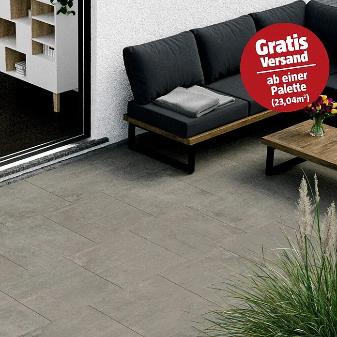 Terrassenfliese Garden Grey - 60 x 60 x 2 cm, Grau, Matt - Dunkelgraue Terrassenfliesen bilden einen Außenboden neben einem modernen Sofa.
