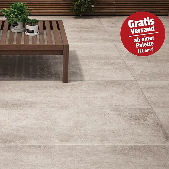 RAK Ceramics Terrassenfliese Volterra 2.0 - 60 x 120 x 2 cm, Sandgrau, Matt - Helle, steinoptische Outdoor-Fliesen auf einer Terrasse. Im Vordergrund steht ein Holztisch mit Topfpflanzen.