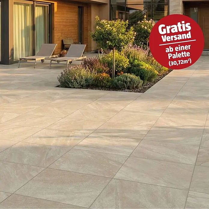 Terrassenfliese Quarzo - 80 x 80 x 2 cm, Beige, Matt - Große, beigefarbene Terrassenplatten mit Natursteinoptik in einem Außenbereich neben einem Garten verlegt.