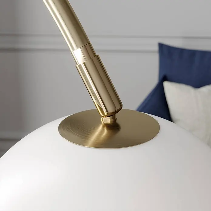 Lindby Stehleuchte Cynthia - Höhe: 140 cm, messing / gold, E27 - Nahaufnahme: goldener Lampenarm trifft weißen Kugelschirm mit gebürsteter Messingplatte.