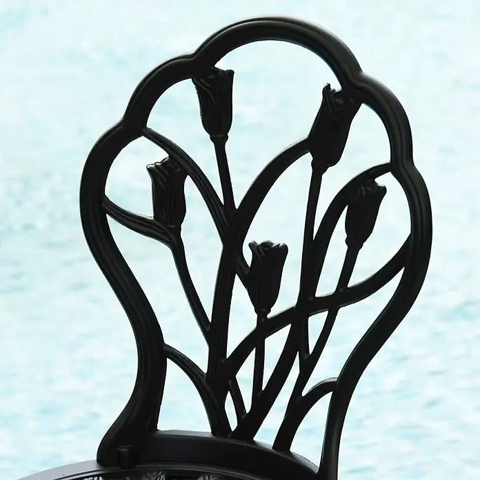 Outsunny Gartenstuhl-Set 3-teilig, mit Tisch -  - Dunkle, verzierte Metallstuhl-Rückenlehne mit Tulpenmuster, vor hellblauem Wasserhintergrund.