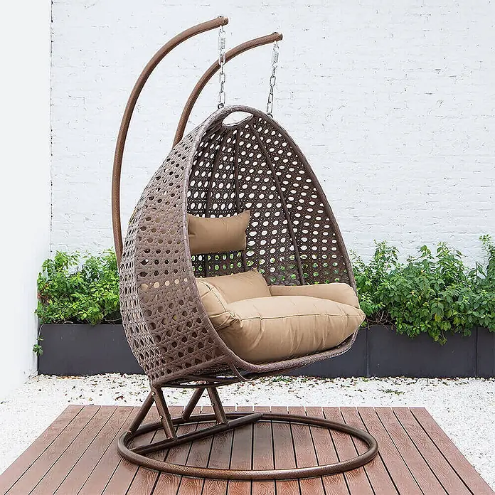 Home Deluxe Hängesessel TWIN - Kunststoff, Braun - Brauner Rattan-Hängesessel mit beigen Kissen auf einer Holzterrasse im Freien.