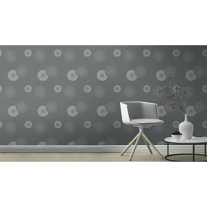 Rasch Tapetenwechsel Vliestapete - Dunkelgrau, Grafisch, 10,05 x 0,53 m - Ein moderner Sessel mit hellgrauem Bezug und Holzbeinen vor einer grauen Wand mit Muster.
